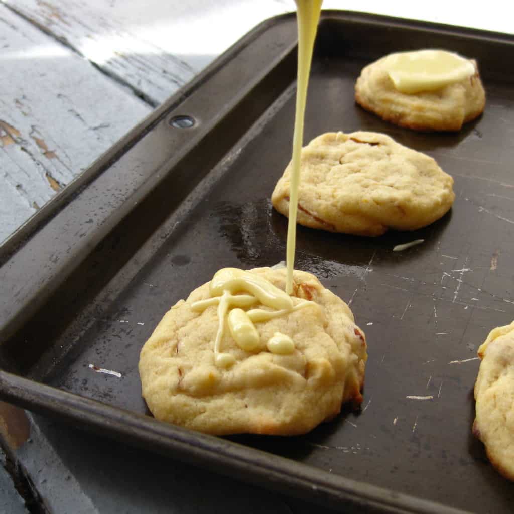 glaze being poured on vegan orange almond cookies