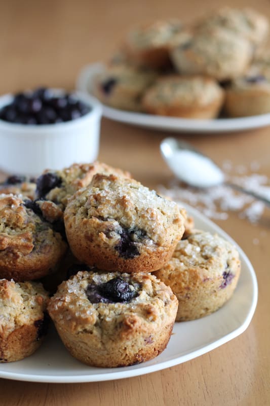 stack of vegan blueberry muffins on white plate with wood backdrop