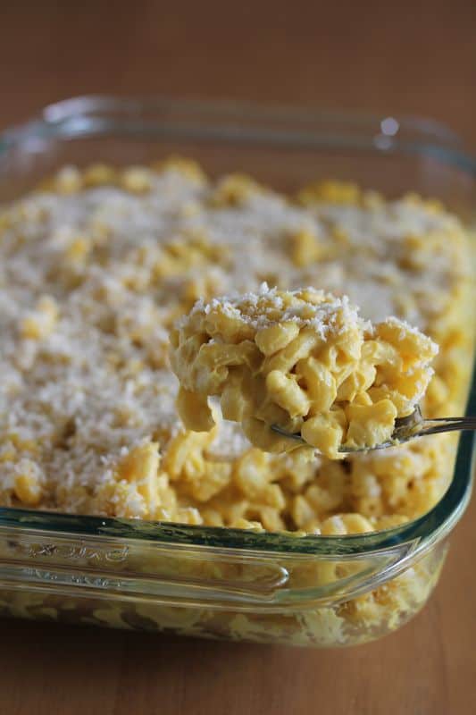 spoonful of vegan cauliflower Mac and cheese with glass baking dish in background