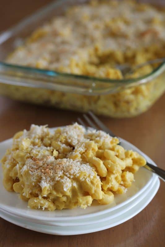 vegan cauliflower Mac and cheese on small white plate with wooden background and casserole dish in background