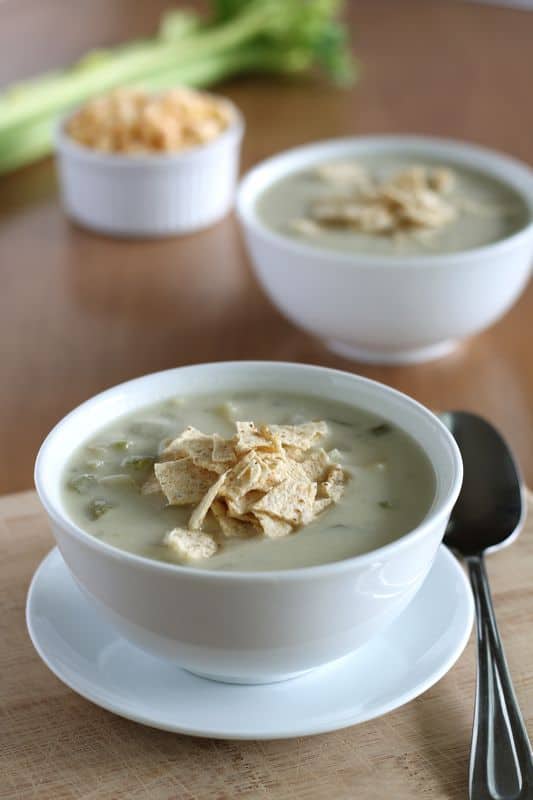 vegan creamy potato soup in white bowl with wood background and second bowl of soup behind.