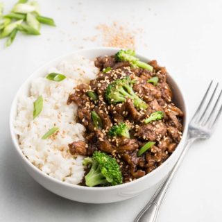 vegan beef and broccoli in white bowl with fork and white background