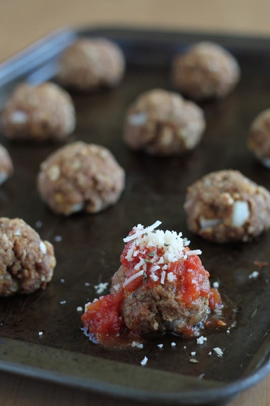 sweet and sour meatballs on baking sheet with tomato sauce on top