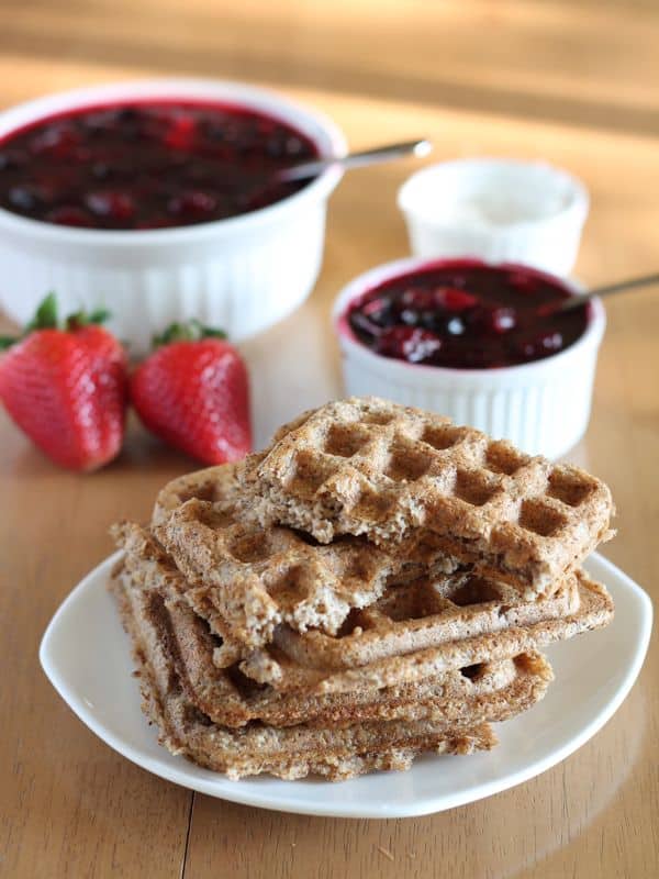 healthy vegan waffles stacked on white plate with wood background