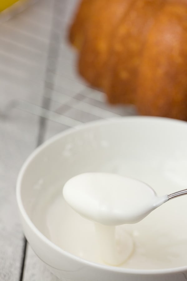 lemon glaze for vegan lemon cake in white bowl with spoon