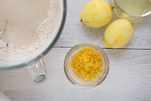 grated lemon rind in small glass bowl, with flour/sugar mixture in clear glass mixing bowl on the side