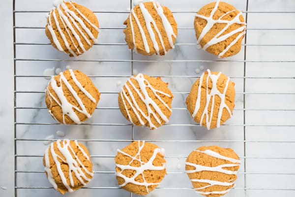 vegan pumpkin cookies drizzled with white icing, sitting on cooling rack