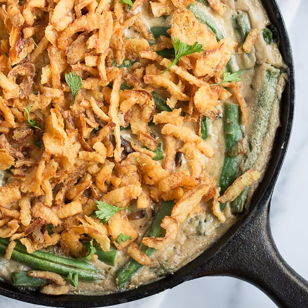 vegan green bean casserole topped with crispy fried onions in a cast iron skillet