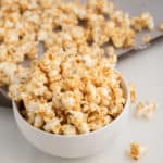vegan caramel popcorn in white bowl with sheet pan in the background