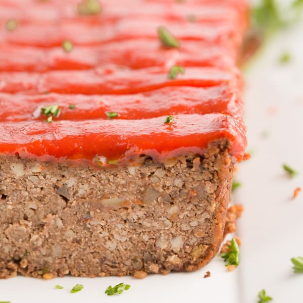 vegan meatloaf with maple tomato glaze and parsley on a white plate