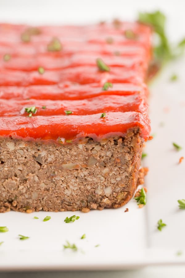 vegan meatloaf with maple tomato glaze and fresh parsley on a white plate