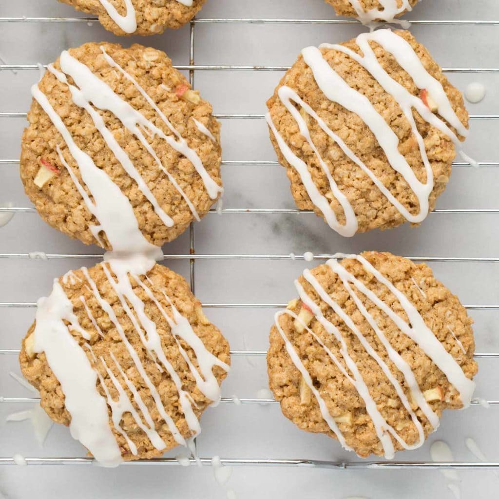 zig-zag iced vegan apple oatmeal cookies on wire rack with marble background
