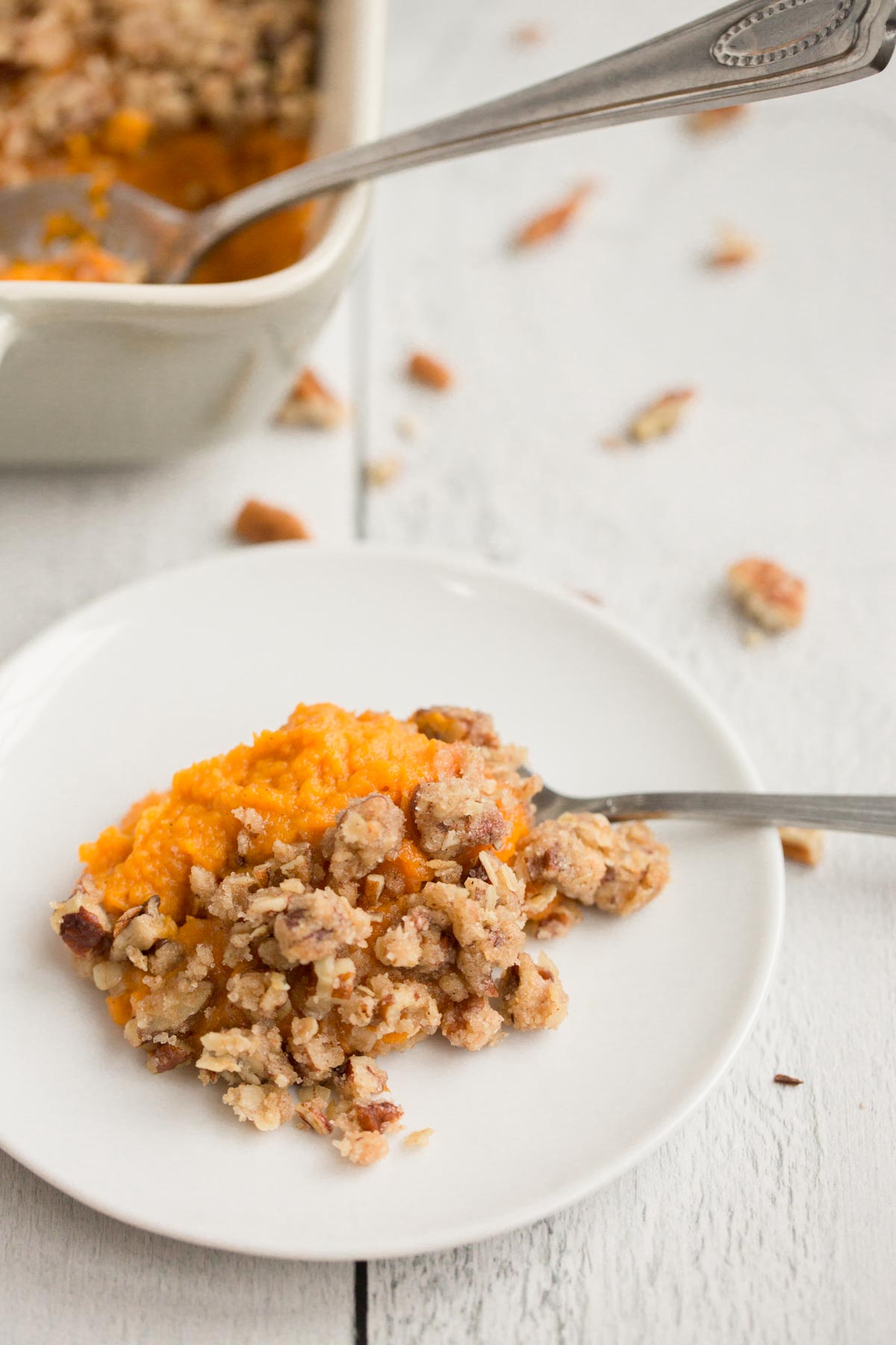 vegan sweet potato casserole on white plate with white wooden background