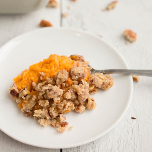 vegan sweet potato casserole on white plate with white wooden background