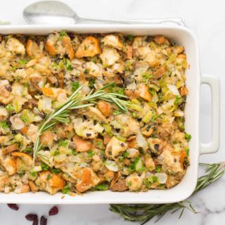 vegan stuffing in white and gray baking dish garnished with rosemary
