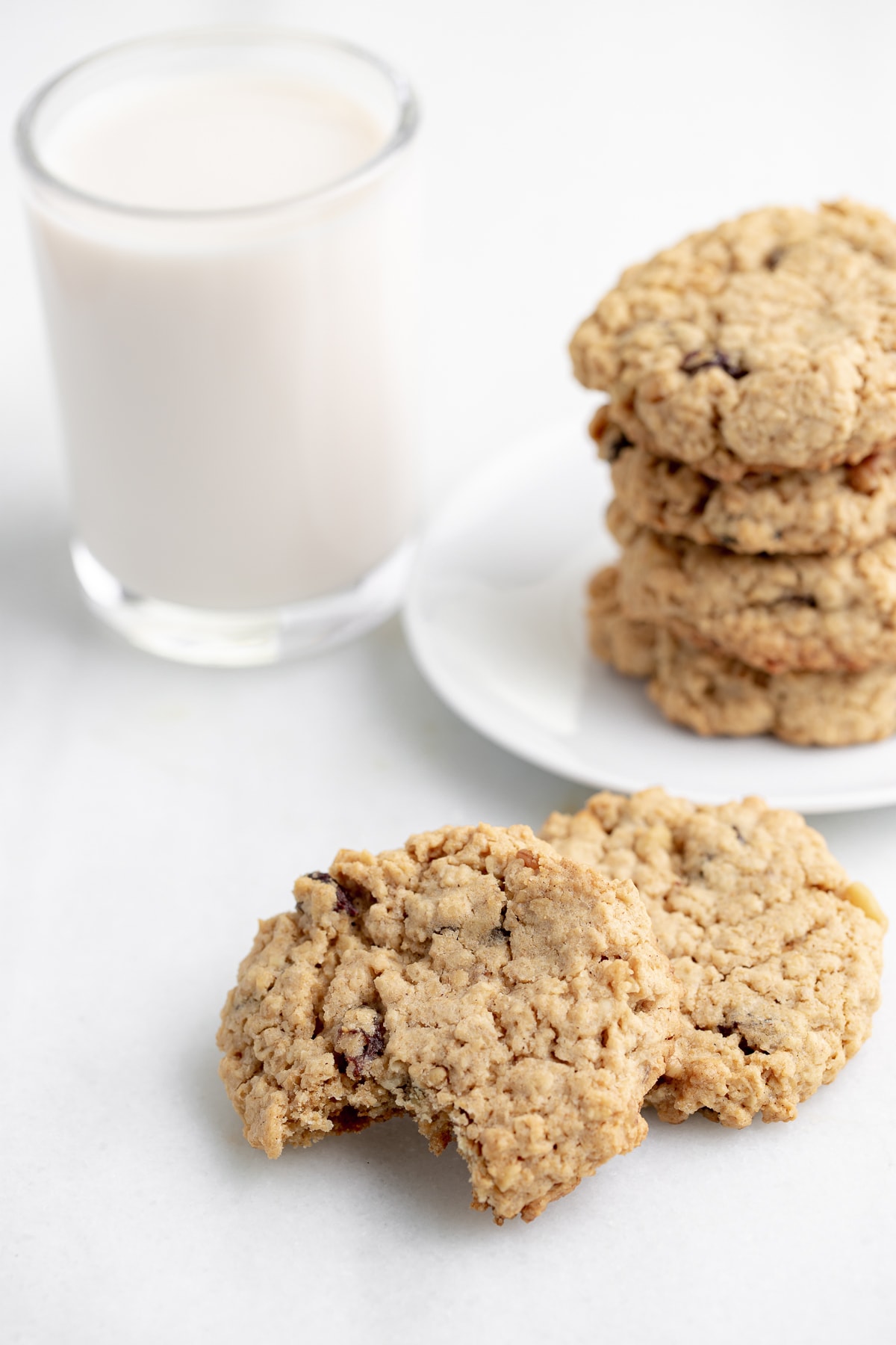 vegan oatmeal cookies with bite taken out of one on white marble background